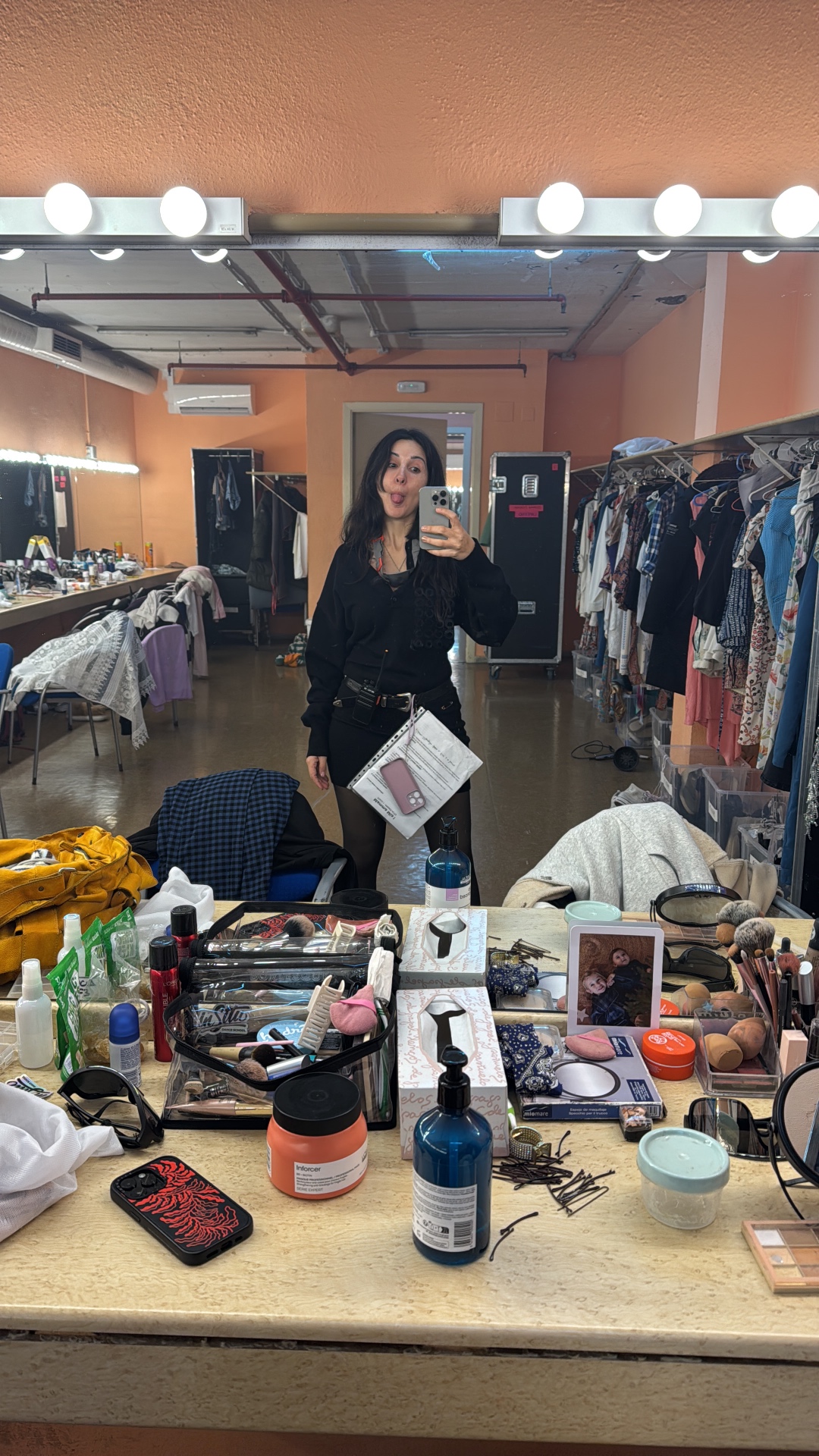 Maya backstage in a wardrobe dressing room with a call sheet and radio