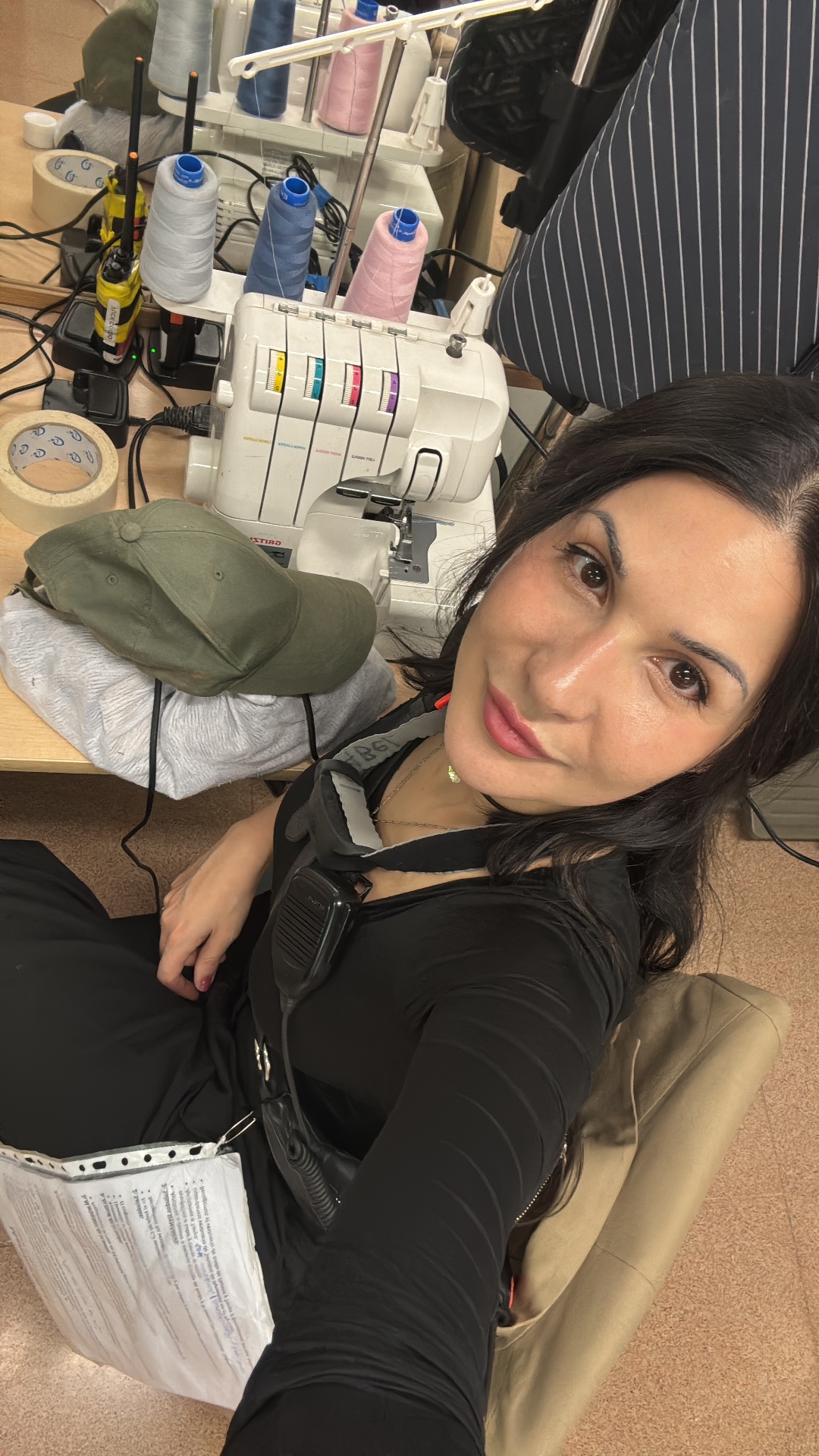 Maya beside an overlock sewing machine in the wardrobe department