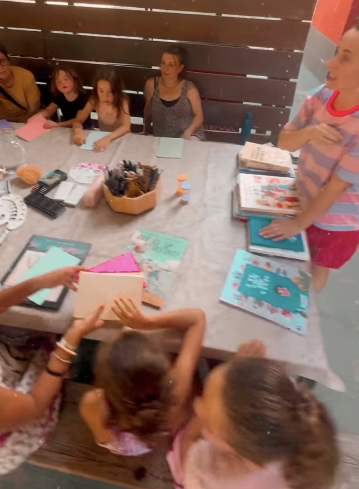 Painting and drawing workshop with adults and children around a table.
